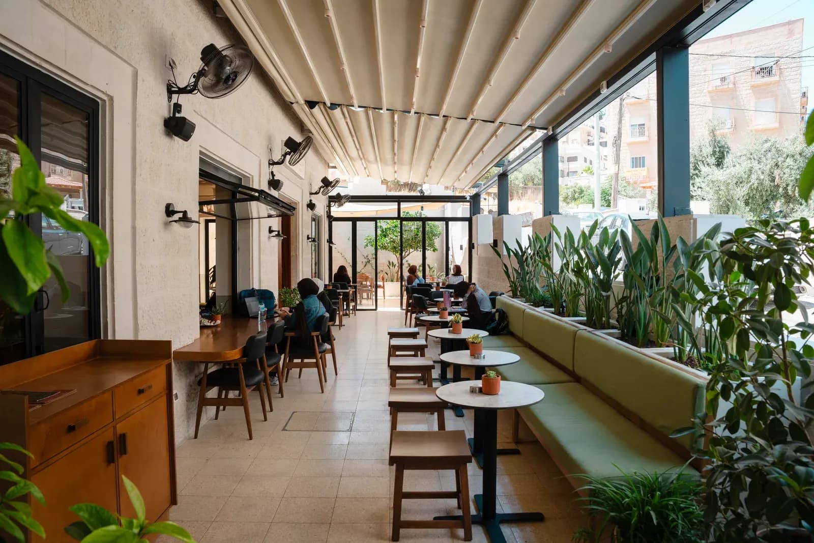 Covered terrace at Asasi Café with café tables and planted bench seating