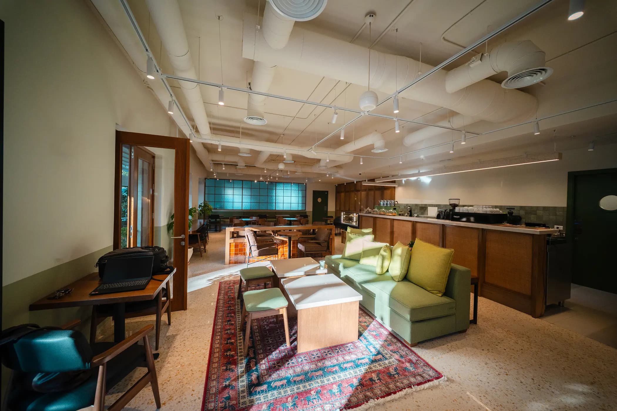 Green upholstered seating, timber chairs and tables inside Asasi Café