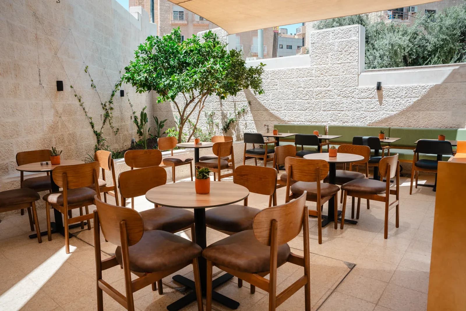 Asasi Café courtyard with timber chairs, round tables and planting